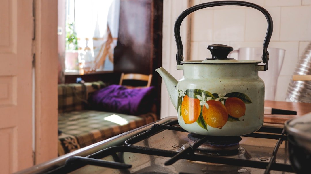 A kettle heating on a clear stovetop with its handle and surrounding space visible.