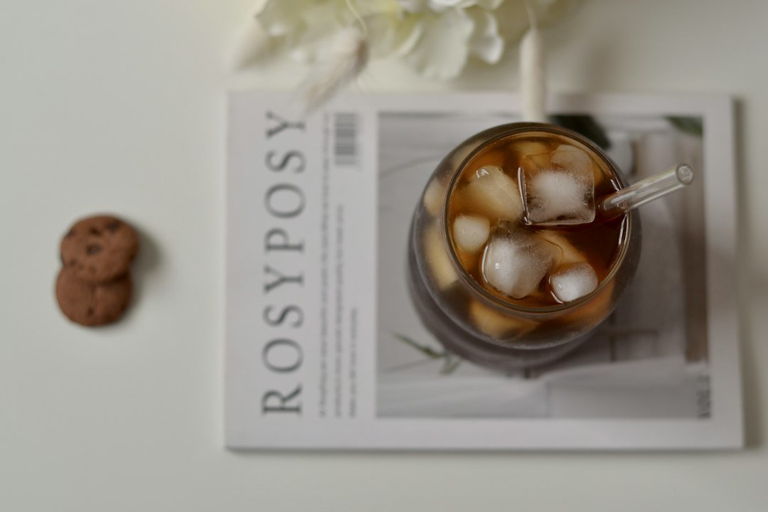 Iced coffee, cookies, and magazine on a white table