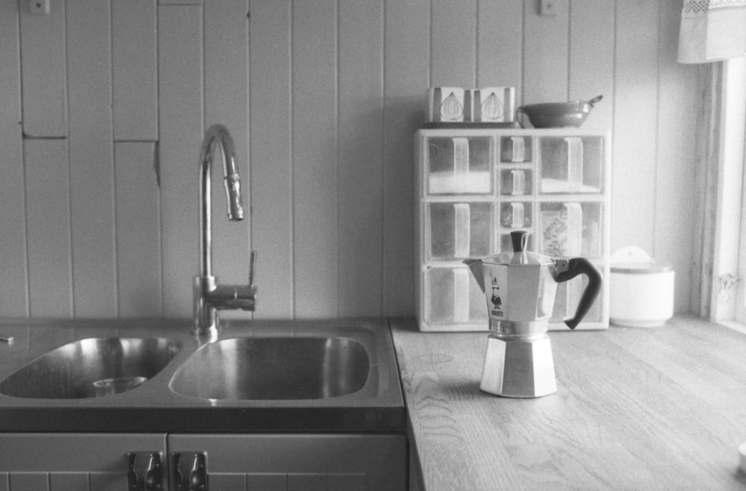A moka pot on a wooden kitchen counter beside a stainless steel sink