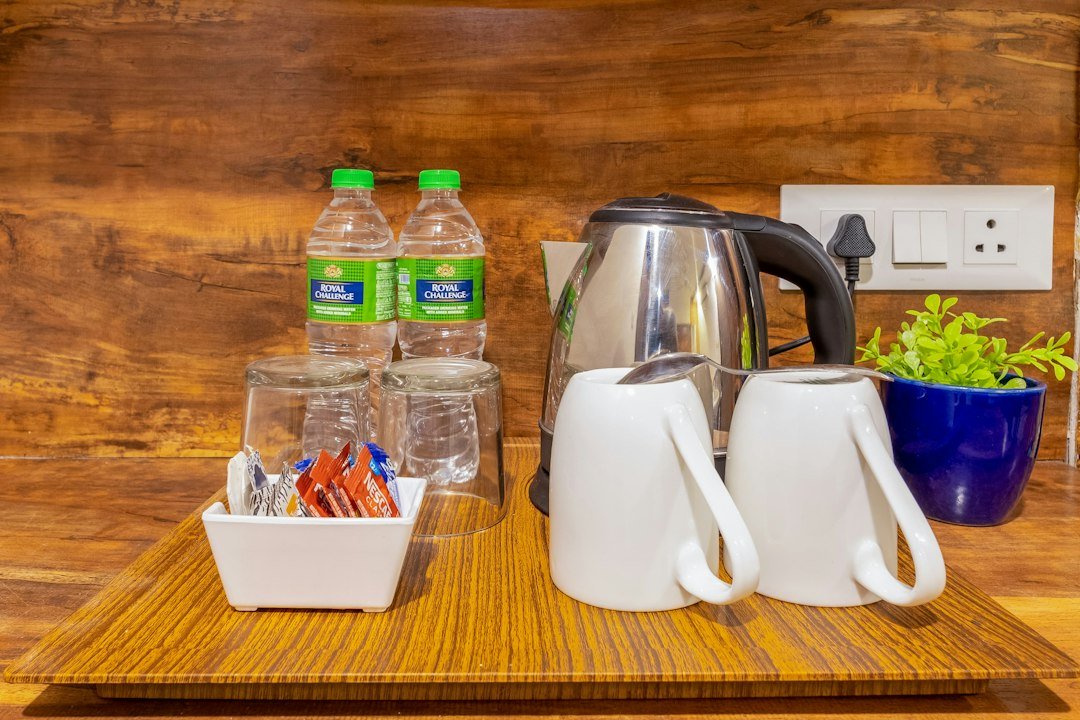 A wooden tray with two water bottles, glasses, mugs, and coffee packets