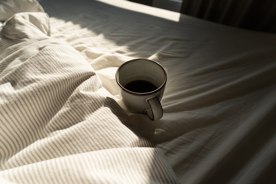 A coffee mug resting on sunlit bedding for a calmer caffeine boundary.