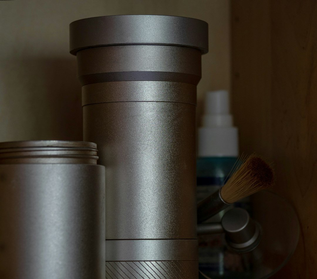 Silver cylindrical containers, a spray bottle, and a makeup brush