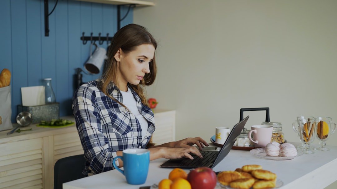 Laptop workspace in a bright kitchen with a coffee break nearby.